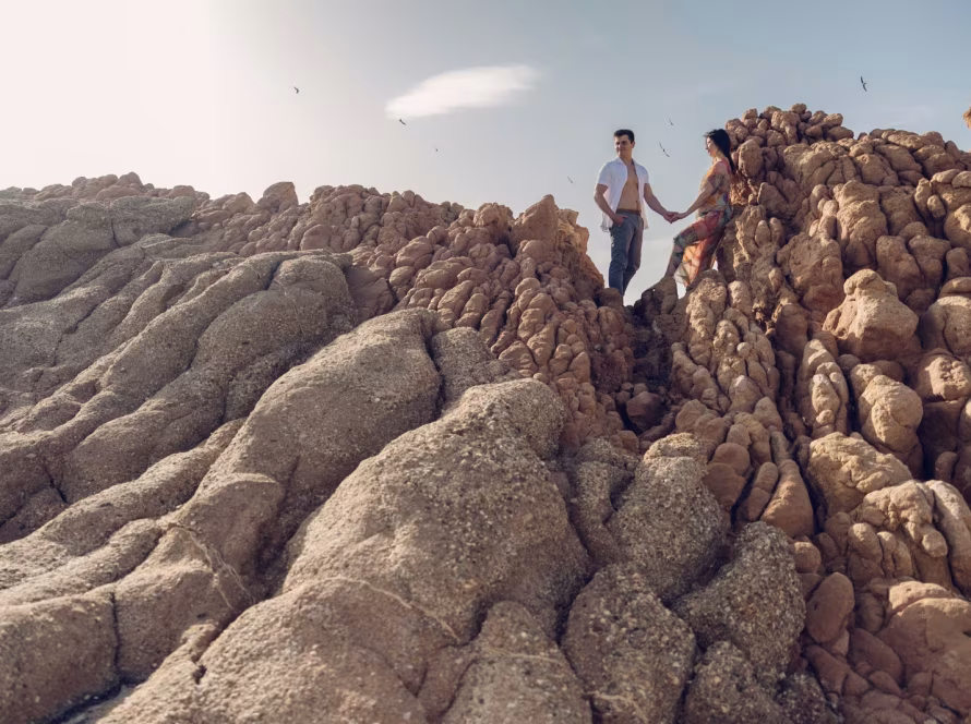 Pregnant couple standing on rocky coast during maternity photoshoot on the Athens Riviera